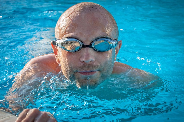 A swimmer breaking the water surface, celebrating a personal best or win.