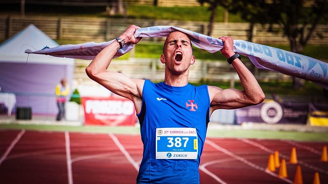 A triumphant athlete raising arms in celebration after winning a race.